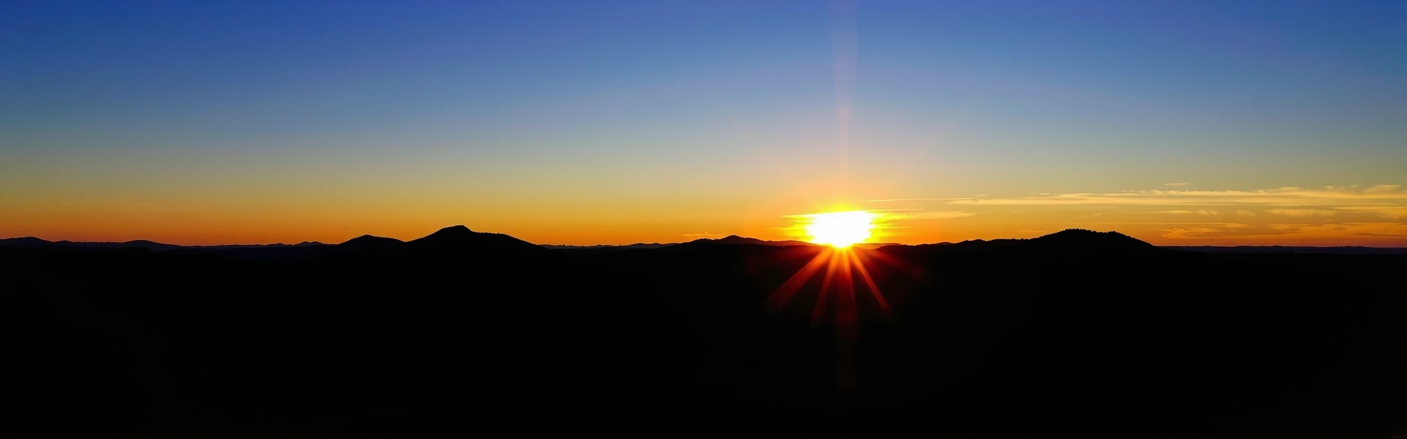 Serene landscape with sun rising over mountains, symbolizing new beginnings and natural wellness.